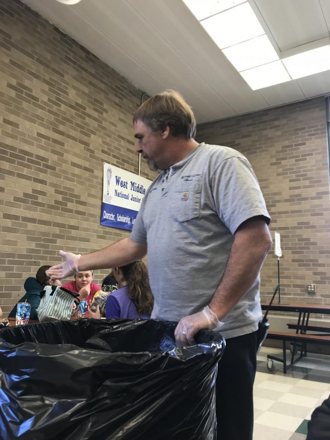 Mr. Kevin reaching for someone’s trash in the cafeteria. 